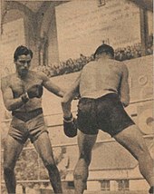Deux boxeurs debout face à face devant une tribune pleine.